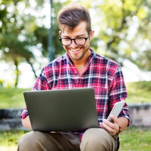 young man smartphone browsing laptop concept PL96PN7