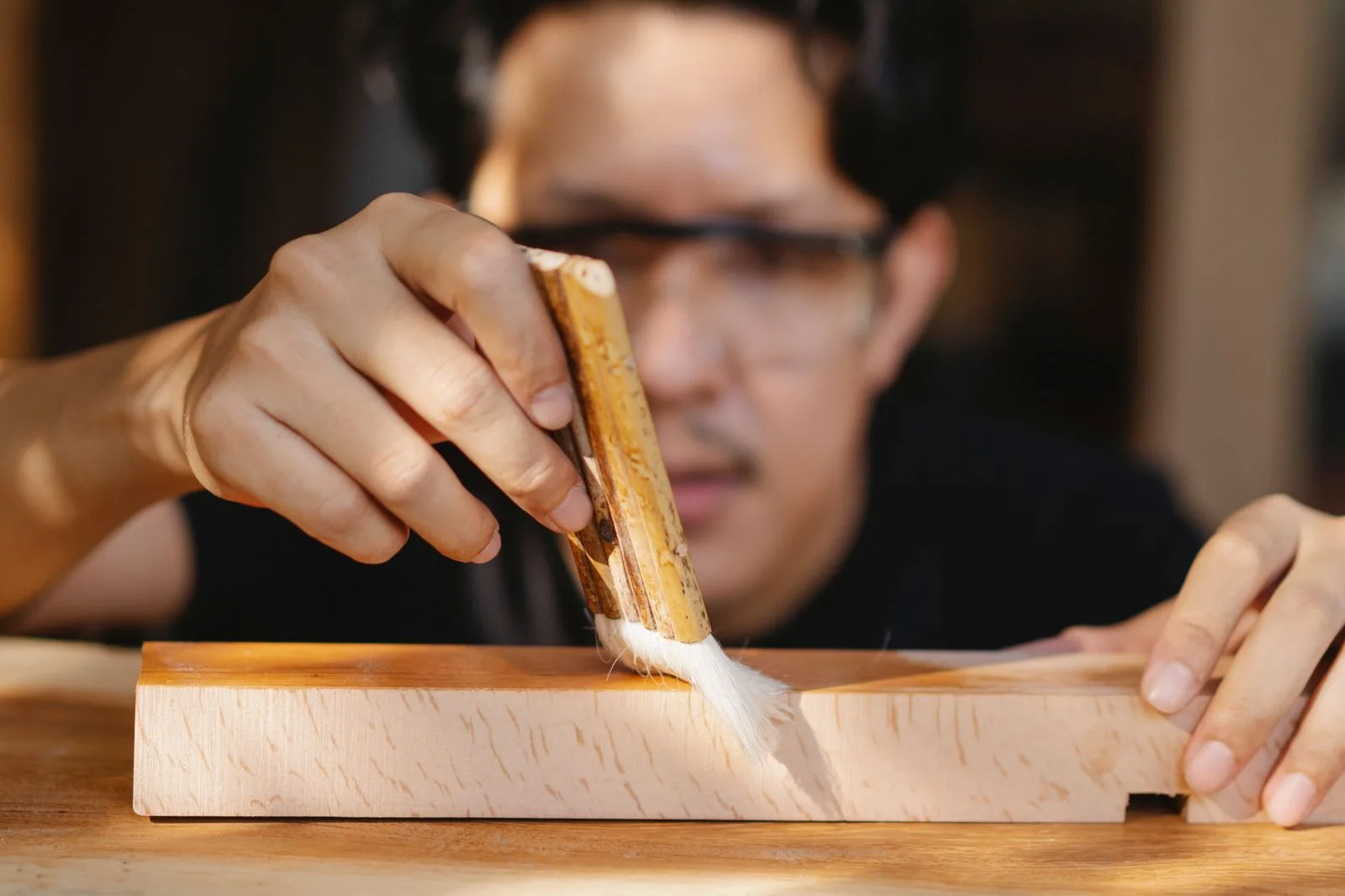 Skilled craftsman applying varnish to wood in a woodworking workshop