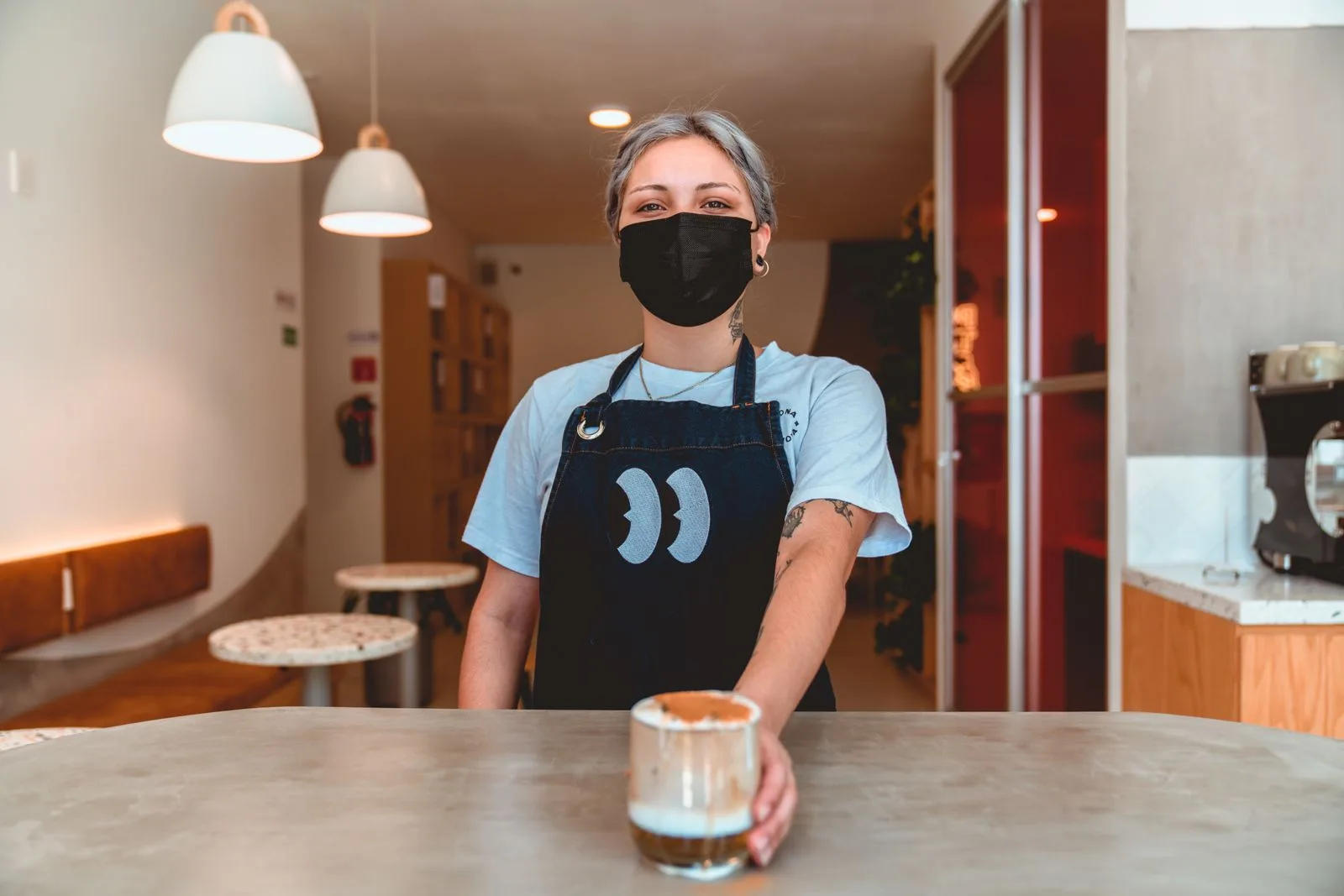A barista serving coffee in a cozy cafe setting
