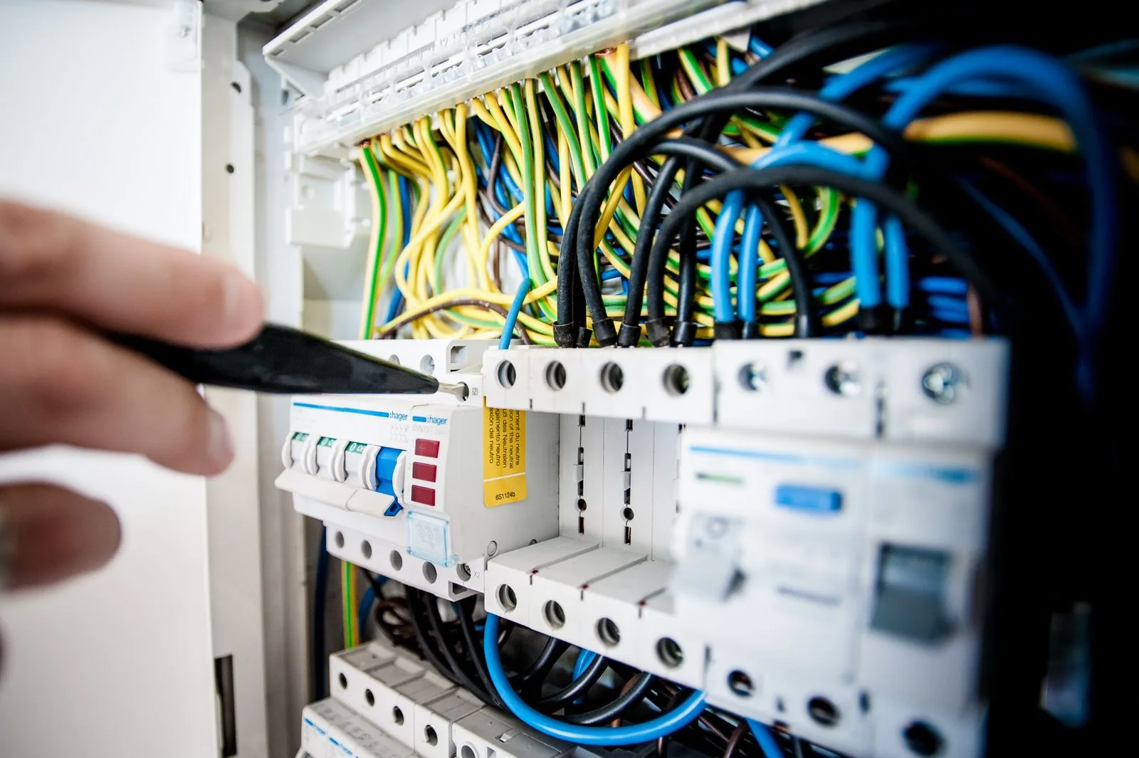 Electrician working on a circuit breaker panel with colorful wires