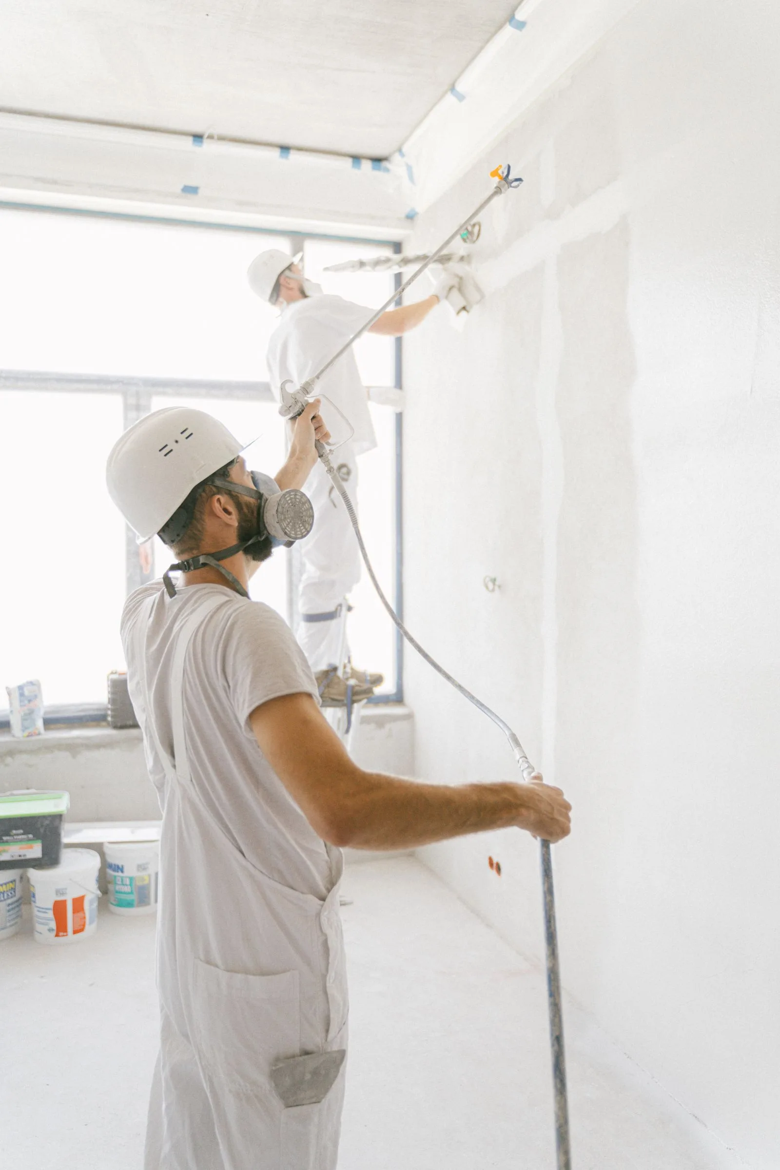 Two professional painters working indoors on a wall renovation project