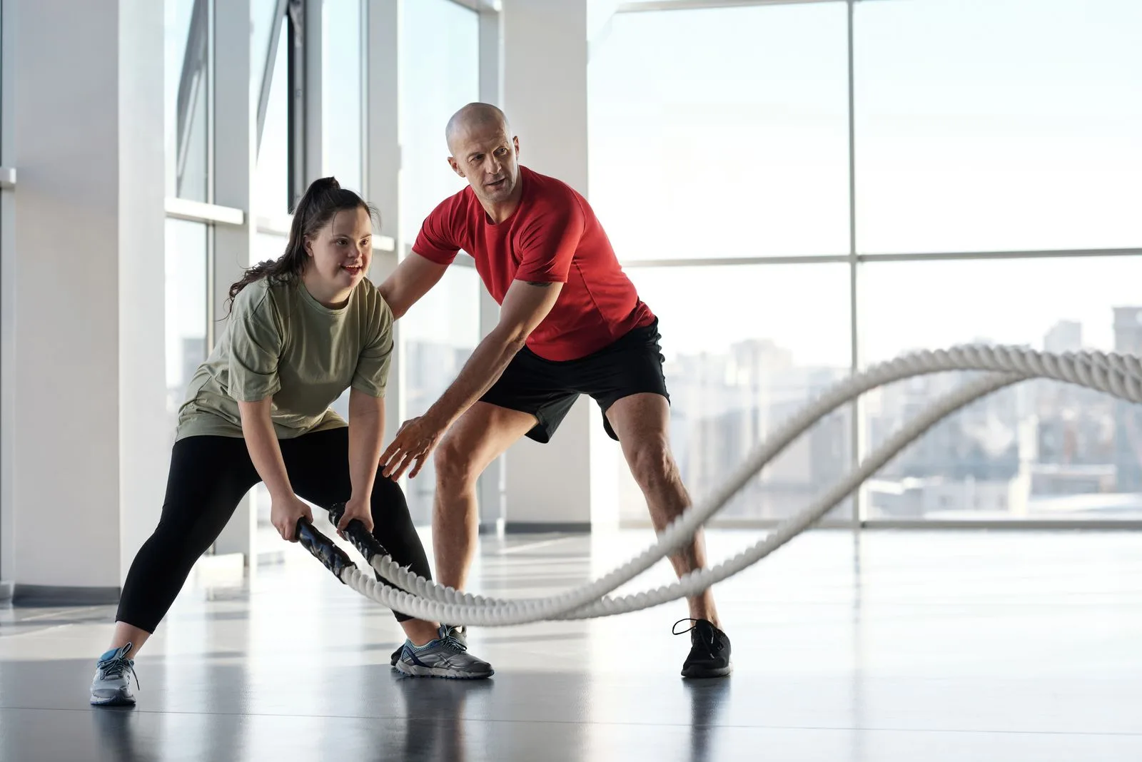 A woman and trainer doing a rope workout in a gym