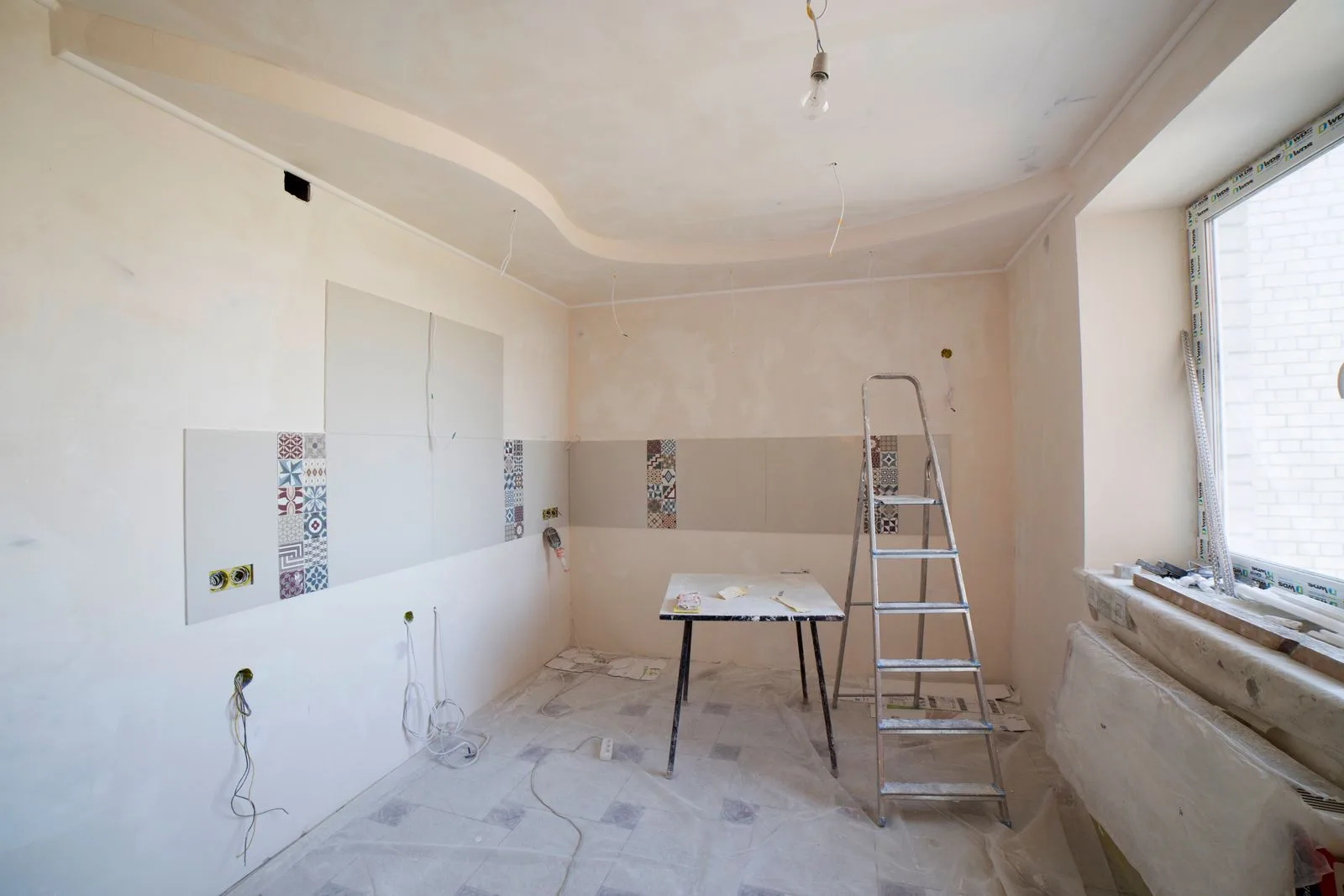 Spacious kitchen under renovation with tools and ladder