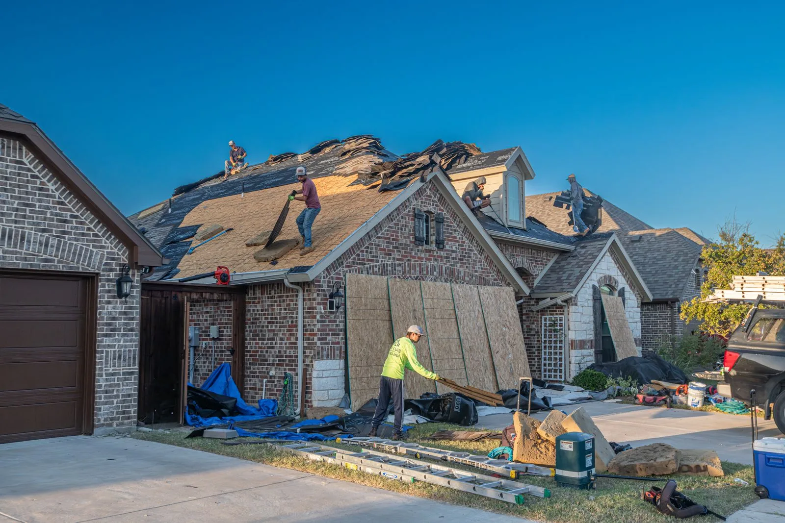Workers engaged in roof replacement on a residential house