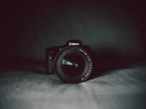 DSLR camera with a zoom lens facing forward on a dark grey cloth